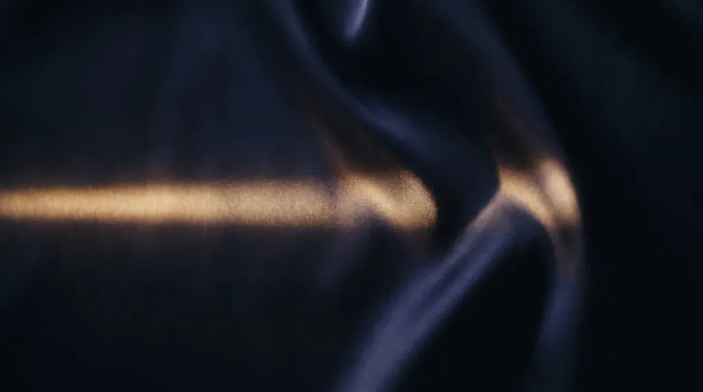 A dark abstract close-up of curved metal catching a strip of light